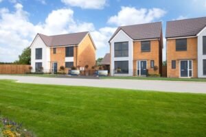 Row of modern detached brick houses with front lawns under a blue sky