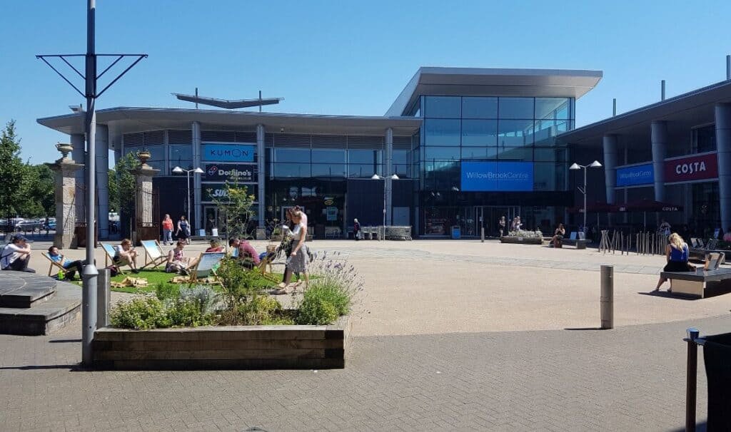 People relaxing outside Willow Brook Shopping Centre in Bradley Stoke on a sunny day.
